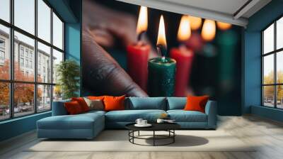 A hand lights a green Kwanzaa candle, symbolizing unity and festive celebration, among other colorful candles, capturing a moment of cultural tradition. Wall mural