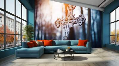 An old rusty beautiful crooked cross stands in the middle of a gloomy forest illuminated by the rays of the setting sun. Wall mural