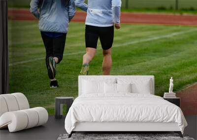 An inspiring and active elderly couple showcase their dedication to fitness as they running together on a lush green field, captured in a close-up shot of their legs in motion. Wall mural