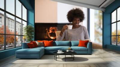 black woman reading book  in front of fireplace Wall mural