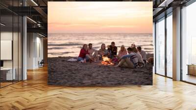 Group Of Young Friends Sitting By The Fire at beach Wall mural