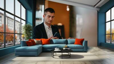 Happy business man sitting at cafeteria with laptop and smartphone Wall mural