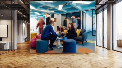 Multiethnic startup business team on meeting in a modern bright open space coworking office. Brainstorming, working on laptop. Group of coworkers walking around in motion blur Wall mural