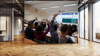 Raised hands and arms of large group of people in class room Wall mural