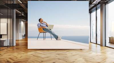 relaxed young man at home on balcony Wall mural