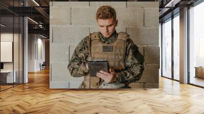 Soldier using tablet computer against old brick wall Wall mural