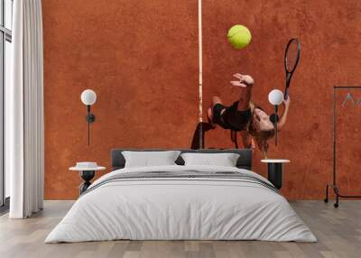 Top view of a professional female tennis player serves the tennis ball on the court with precision and power Wall mural