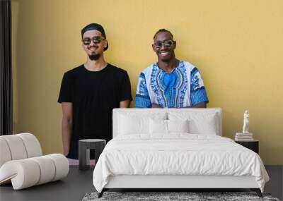 Two Male Friends: African American Teenager in Sudanese Traditional Attire Leaning Against Yellow Wall Wall mural