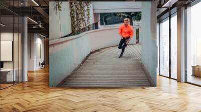 Women in sports clothes running in a modern urban environment et night time. The concept of a sporty and healthy lifestyle Wall mural