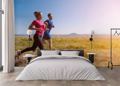 young couple jogging on sunny day at summer mountain Wall mural