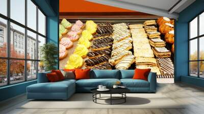 Tasty French eclairs with icing, a variety of cream cakes and raisin buns. Wall mural