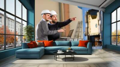 Two businessman working with laptop in factory Wall mural