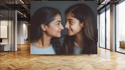 A studio portrait of an Indian mother and daughter looking at each other and smiling Wall mural