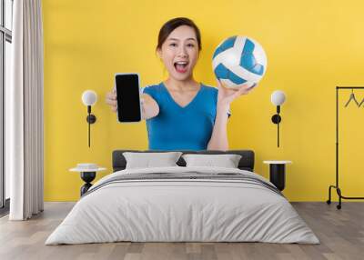 Beautiful Asian woman posing with soccer ball on blue background Wall mural