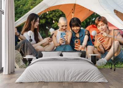 Image of a group of young Asian people laughing together and using their phones Wall mural