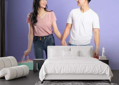 image of asian couple holding shopping bags on purple background Wall mural