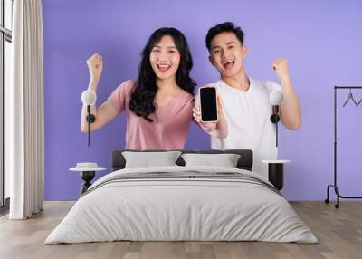 image of asian couple holding smartphone, isolated on purple background Wall mural