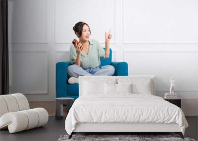 image of young Asian girl sitting on sofa at home Wall mural