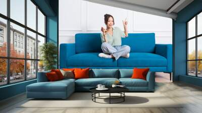 image of young Asian girl sitting on sofa at home Wall mural