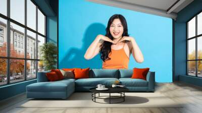 Portrait of a beautiful asian girl in a swimsuit smiling happily on a blue background Wall mural