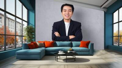 Young business man wearing a suit posing on a grey background Wall mural