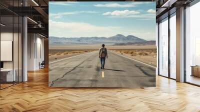 A person walking along an empty road in a desolate landscape with blue sky Wall mural