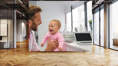 Doctor with an infant in the pediatrics area. The doctor conducts an kid examination in his office . Happy expression Wall mural