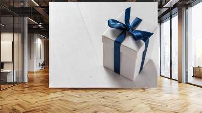 A white present box with blue satin ribbon on white wooden background Wall mural