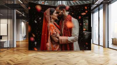 An indian bride and groom embracing in the red fabric wedding costume with red flowers petals falling down, generative ai Wall mural