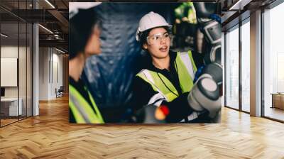 Female technician engineer using controller checking and operating automatic robotic machine at industrial factory, Worker working with robotic arms system in factory Wall mural