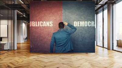 Puzzled businessman and a split wall with Democrats versus Republicans, red vs blue sides. Correct choice, left or right. Difficult decision and doubt concept. Future presidential elections. Wall mural