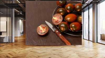 Dark red tomatoes on a metal grill. Two halves of a red tomato and a knife. Wall mural