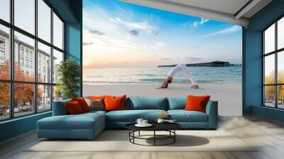 Asian woman practicing yoga Downward Facing Dog or Adho Mukha Svanasana Pose stretching exercises muscle for warm up on the beach in Maldives with sunset,Feeling so comfortable and relax in holiday Wall mural