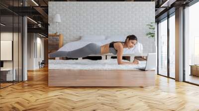 Attractive Asian woman looking laptop practice yoga plank online course at home to meditation comfortable and relax,Health care and Exercise at home Concept,Self-isolation due COVID-19 pandemic Wall mural