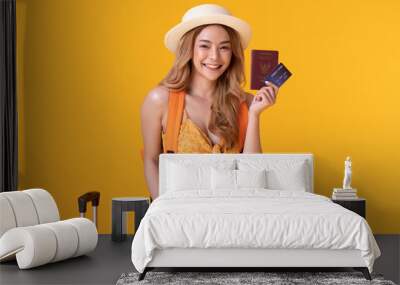 Cheerful Backpacker Traveler tourist asian woman with travel bags and summer hat ready to traveling and holding credit card and passport,isolated on yellow background,Travel and vacations concept Wall mural