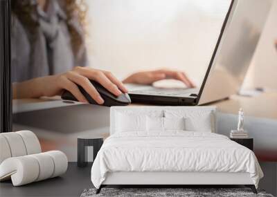 Close up hand of business asian young woman with curly hairstyle holding digital computer mouse and clicking working with computer laptop.Female freelancer using wireless mouse on desk at home Wall mural