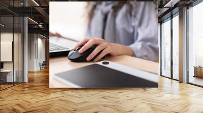 Close up hand of business asian young woman with curly hairstyle holding digital computer mouse and clicking working with computer laptop.Female freelancer using wireless mouse on desk at home Wall mural