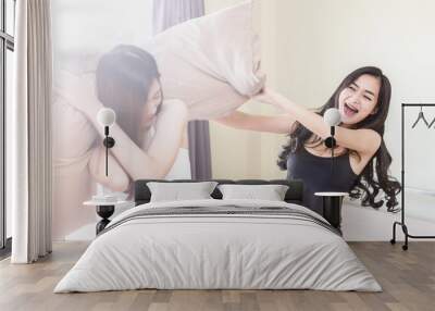 two woman friends playing pillow in bedroom feeling so fun and happiness Wall mural