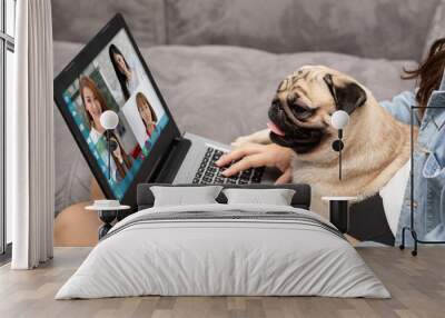 Woman working on laptop with dog Pug breed at home,woman VDO Call Conference to meeting business team during quarantine coronavirus sitting on sofa at home,Video conference work from home concept Wall mural