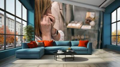 woman trying on earrings in a store in front of a mirror Wall mural