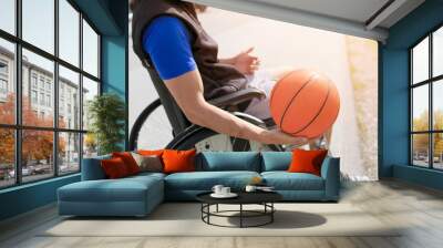 Disabled young basketball player on a wheelchair holding ball and beeing active in sport Wall mural