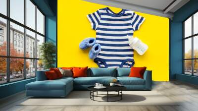 Blue bodysuit for baby boy near children's accessories on yellow background top-down Wall mural