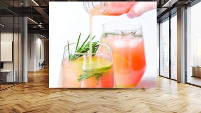 pouring fresh juice in glass with lime and rosemary on white bac Wall mural