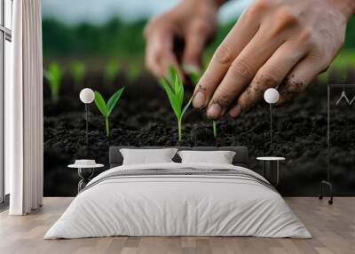 A close-up of hands planting green seedlings in rich soil, showcasing the nurturing process of growth in a vibrant garden. Wall mural