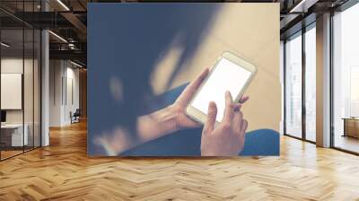 Young woman holding smarthphone in hand Wall mural