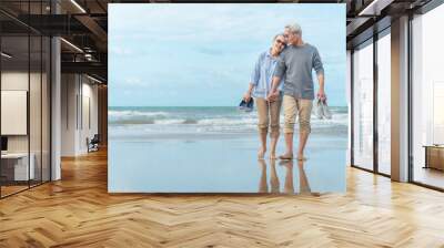 Age, Travel, Tourism and people concept - happy senior couple holding hands and walking on summer beach Wall mural