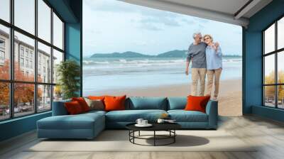 Age, Travel, Tourism and people concept - happy senior couple holding hands and walking on summer beach Wall mural