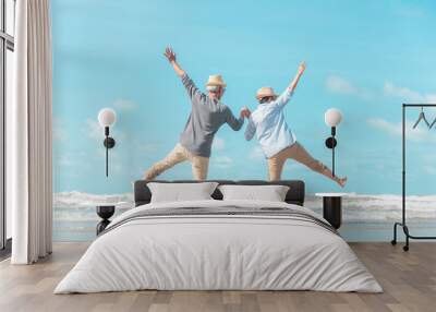 Charming elderly couple went to the beach to enjoy the sea breeze Wall mural