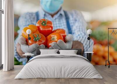 A man wearing a blue apron is holding a bunch of tomatoes Wall mural