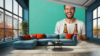 Portrait of cheerful funky young man open mouth hands hold glass beer bottles isolated on green color background,copy space. Wall mural